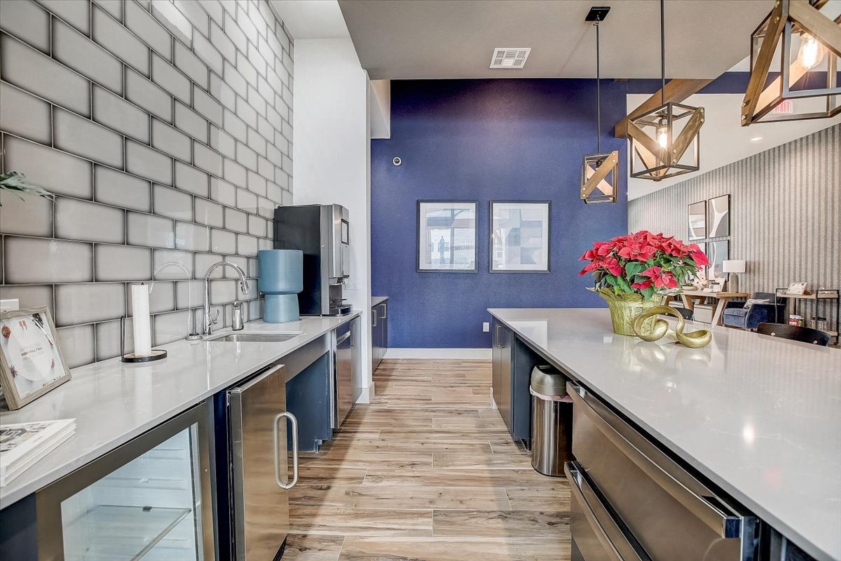 Community kitchenette with subway tile backsplash, beverage station, and stainless mini fridge for refreshments.